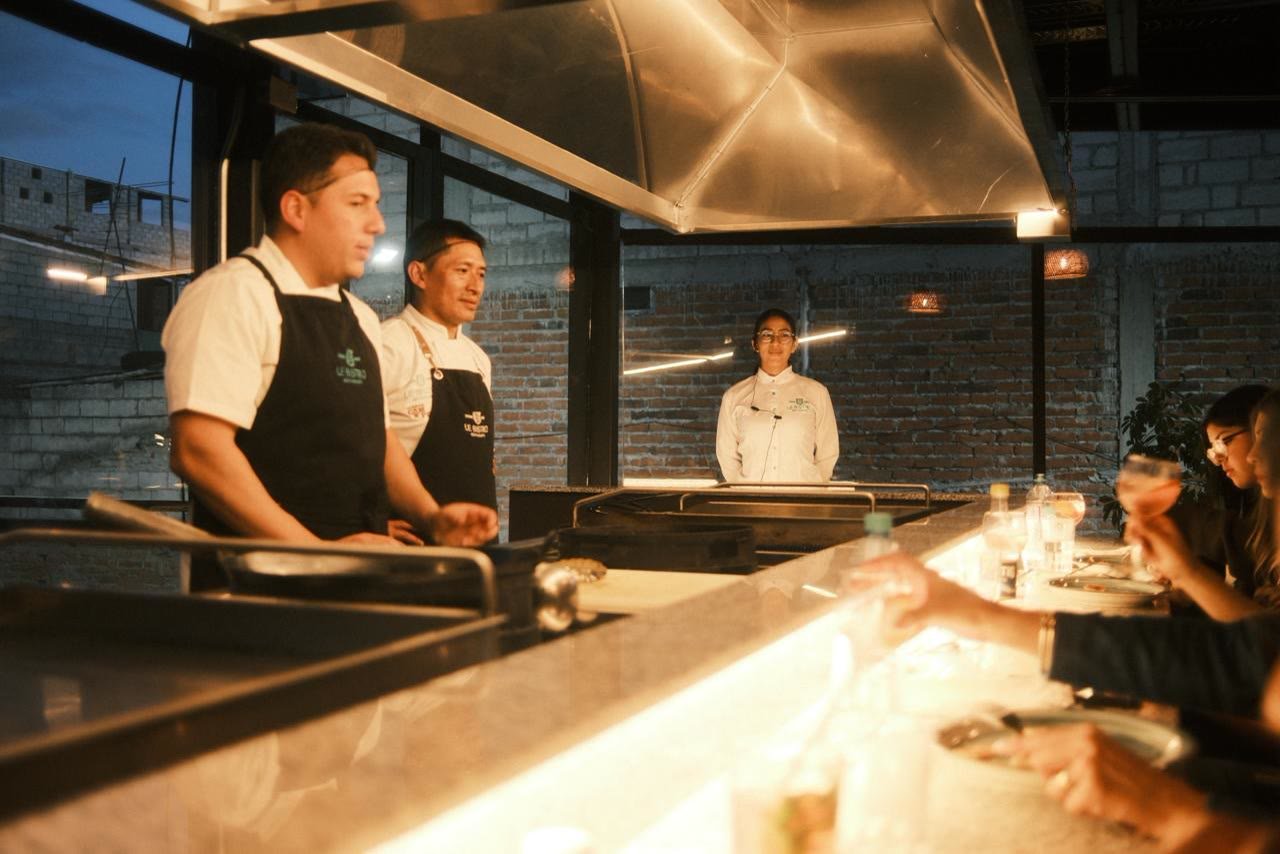 Chefs conversando con los invitados sentados en la barra iluminada