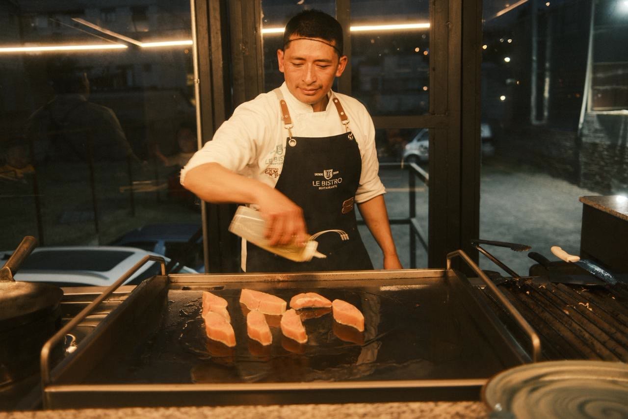 Chef aceitando piezas de pescado sobre la plancha